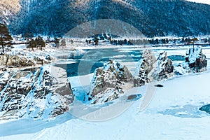 Winter landscape with rocks, stones and ice in the river. The trees and stones are covered with snow