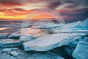 Winter landscape on seashore during sunset. Lofoten islands, Norway. Ice and sunset sky.