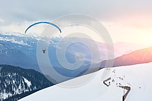 Winter landscape of a ski resort. Outdoor activities for skiers and paragliders. Sunrise or sunset in the mountains