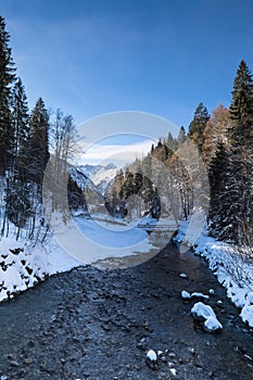 Winter landscape with snow-covered forests and a boulder-strewn river