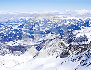 Winter landscape with snow covered slopes and blue sky, with Aerial view of Zell am See lake from the top of