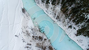 Winter landscape with snow forest and the blue river captured from above with a drone.