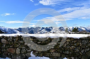 Winter landscape with snowy stone wall and mountains. Lugo, Galicia, Spain.