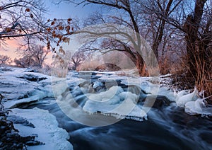 Winter landscape with snowy trees, beautiful frozen river at sun