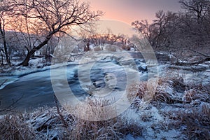 Winter landscape with snowy trees, beautiful frozen river at sun