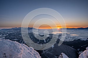 Winter landscape at sunrise from Velky Choc mountain in winter with fog in valley, view of low and high Tatras and Liptovska Mara