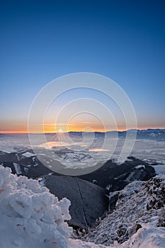 Winter landscape at sunrise from Velky Choc mountain in winter with fog in valley, view of low and high Tatras and Liptovska Mara