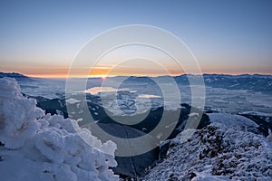 Winter landscape at sunrise from Velky Choc mountain in winter with fog in valley, view of low and high Tatras and Liptovska Mara