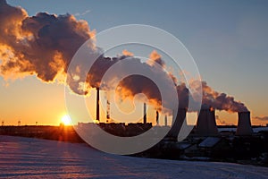 Winter landscape during sunset with steaming factory