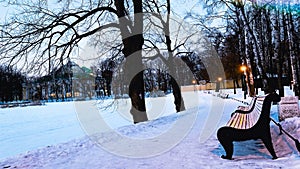 Winter landscape with trail in snowy winter park and wooden benches with view on frozen lake and palace. Travel Saint