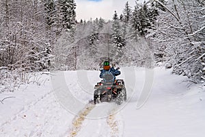 Winter landscape - view of the snowy road with a quad bike in the winter mountain forest