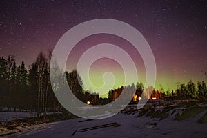 Winter landscape with wooden house under a beautiful starry sky and Northern Lights