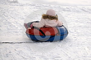 Winter, leisure, sport, friendship and people concept - happy people sliding around on snow tubes