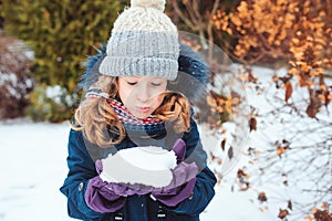 Winter lifestyle portrait of happy kid girl playing snowballs on the walk