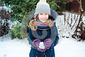 Winter lifestyle portrait of happy kid girl playing snowballs on the walk