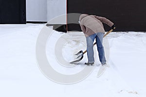 Winter is a lot of snow. A young girl, cleans, proud of doing the big shovel work