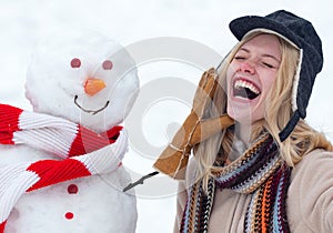 Winter love concept. Happy girl plaing with a snowman on a snowy winter walk. Making snowman and winter fun. Crazy