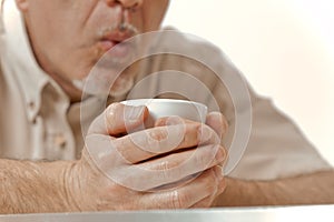 Winter morning man blows on hot coffee