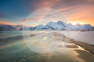 Winter morning over the sea and mountains, colorful northern sunrise and sunlight in pink clouds