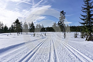 Winter mountain landscape with groomed ski track and blue sky in sunny day.