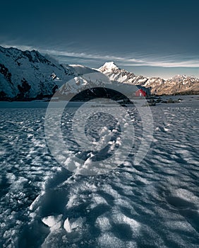 Winter mountain landscape with Mt Cook peak and red hut in the background, New Zealand