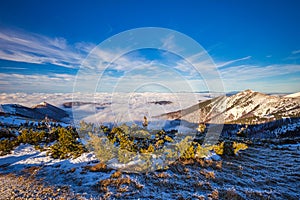 Winter mountain landscape at a sunny day with fog in the valleys