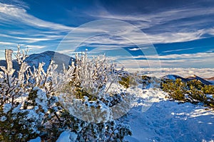 Winter mountain landscape at a sunny day with fog in the valleys