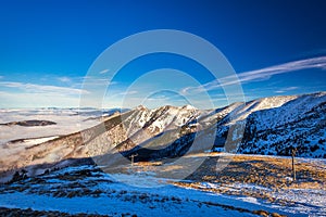 Winter mountain landscape at a sunny day with fog in the valleys