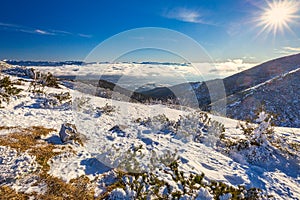 Winter mountain landscape at a sunny day with fog in the valleys