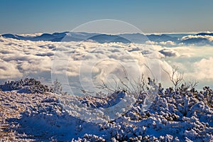 Winter mountain landscape at a sunny day with fog in the valleys