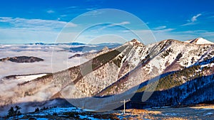 Winter mountain landscape at a sunny day with fog in the valleys