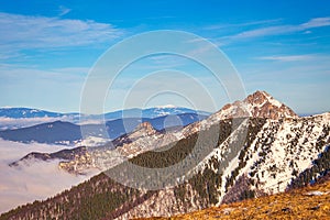 Winter mountain landscape at a sunny day with fog in the valleys