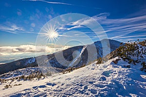 Winter mountain landscape at a sunny day with fog in the valleys