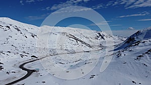 Winter mountain pass road cutting throught white winter landscape surrounded by tall peaks on the Kaperdalen mountain on the islan