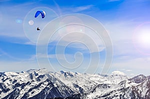 Winter mountains landscape and man paragliding