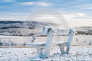 Winter mountains landscape and wooden iced bench in the morning