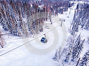 Winter mountains with ski lifts and snowy forest, aerial top view