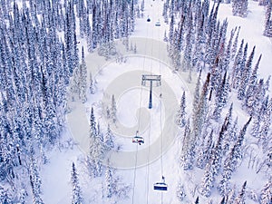 Winter mountains with ski lifts and snowy forest, aerial top view