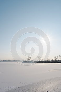 Winter nature landscape. Frosty trees on river side. Winter morning sunrise. Amazing field covered by hoarfrost