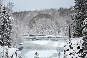 Landscape with a frozen river in the middle of a snow covered forest