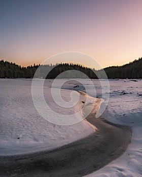 Winter nature. Snowy icy lake shore in mountains. Scenic winter landscape. Beautiful ice mountain lake