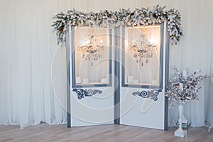 Winter New Year`s photo zone with Christmas-tree decoration, a screen and chandeliers