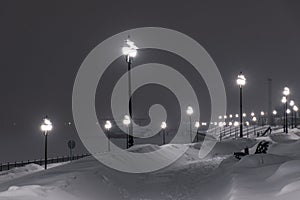 Winter alley night city under snowfall. Street decorative lights in night cityscape