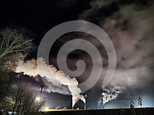 Winter night industrial landscape. Coal-fired power station with smoking chimneys against dramatic dark sky. Air