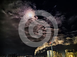 Winter night industrial landscape. Coal-fired power station with smoking chimneys against dramatic dark sky. Air