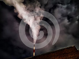 Winter night industrial landscape. Coal-fired power station with smoking chimneys against dramatic dark sky. Air