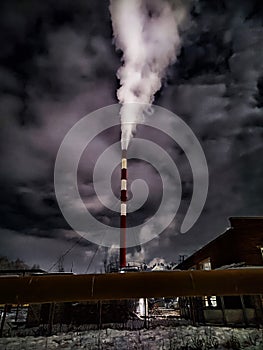 Winter night industrial landscape. Coal-fired power station with smoking chimneys against dramatic dark sky. Air