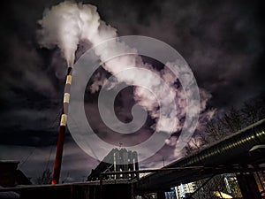 Winter night industrial landscape. Coal-fired power station with smoking chimneys against dramatic dark sky. Air