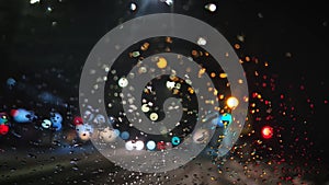 Winter night urban traffic scene as seen through the vehicle window covered with sleet drops