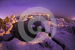 On winter nights, snow and ice cover the rocks by the sea